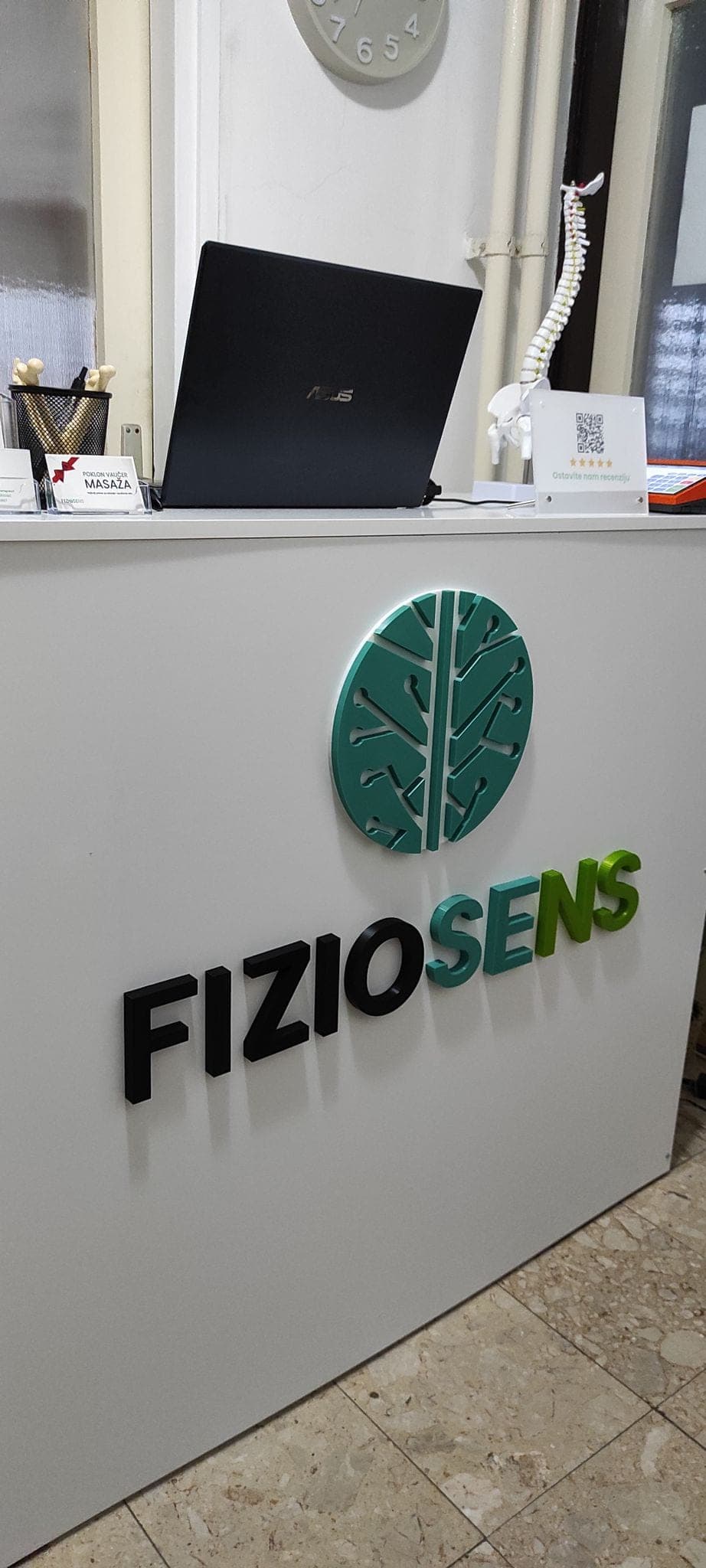 Recepcija sa brendiranim zidom i znakom Fiziosens u kabinetu za fizioterapiju u Leskovcu